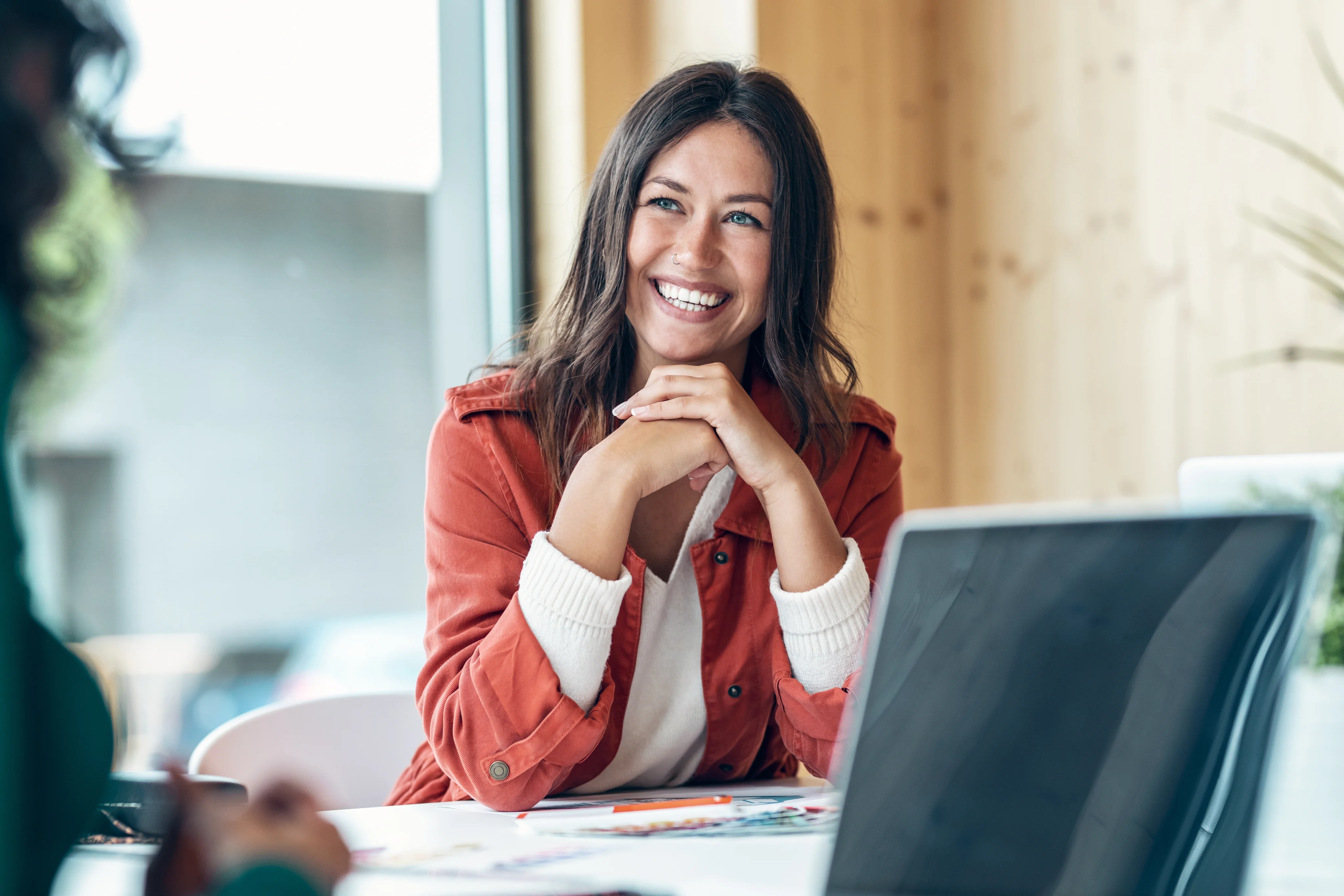 Educator smiling while working on a laptop at a desk.