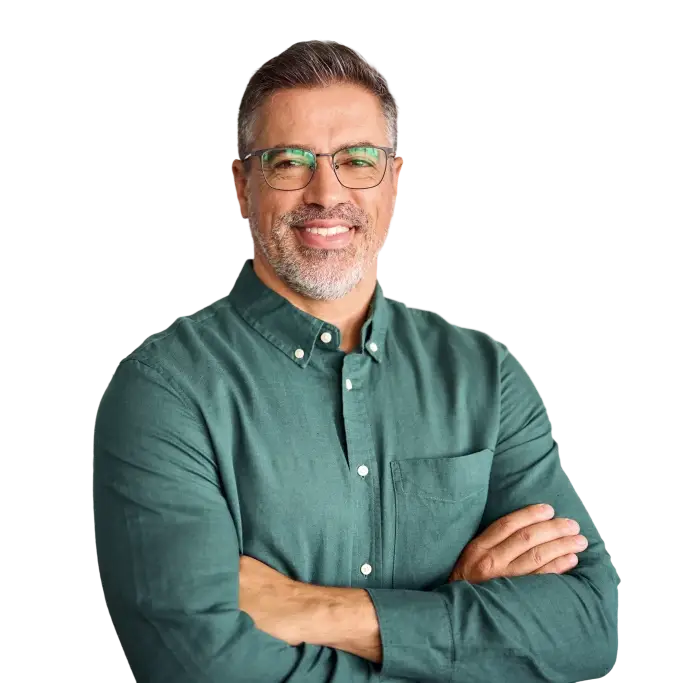 A smiling man with glasses and a gray beard wears a green shirt with crossed arms.
