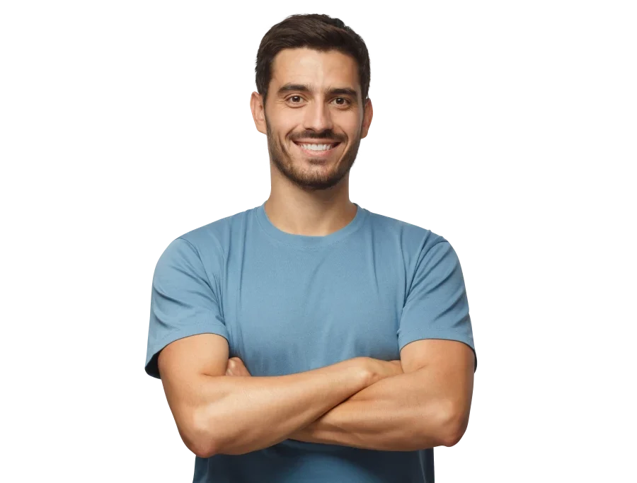 A smiling man in a blue t-shirt stands with his arms crossed.